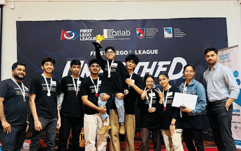 First Lego League team lifting Zahi Najmal while holding trophy after competition victory