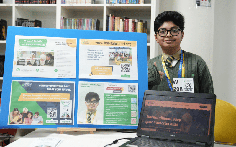 Zahi Najmal presenting Habitat Alumni app on a laptop with a foam board and brochures explaining the project at Digital Fest 2024